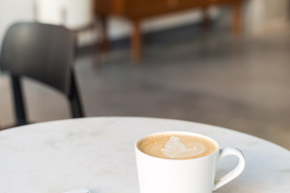 A latte on a cafe table next to a phone, ready to reorder